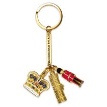 Gold keyring with Buckingham Palace gold rectangle and 3 charms on the end. Charms are a crown, Buckingham palace facade and a guardsman.