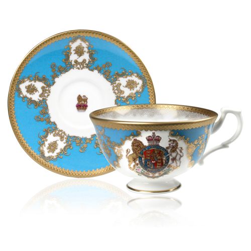 Royal coat of arms fine bone china teacup and saucer featuring a gold rims and a lion and unicorn royal crest surrounded by ornated gold patterns and English flower patterns on a turquoise blue background. 