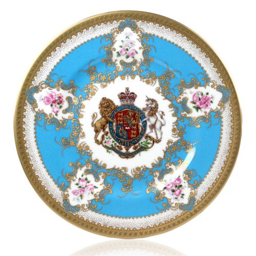 Royal coat of arms fine bone china side plate featuring a lion and unicorn royal crest surrounded by ornated gold patterns and flower patterns on a turquoise blue  background. Gold plated with the words Buckingham Palace, Windsor Castle and Palace of Holy