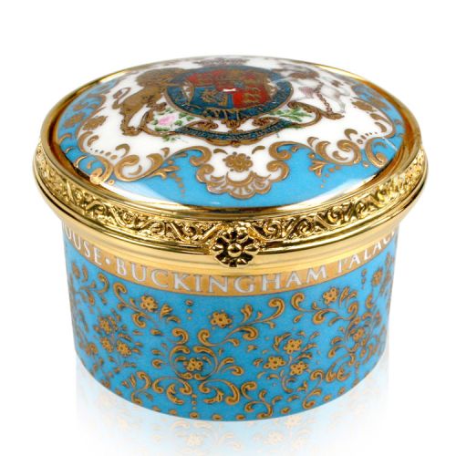 Royal coat of arms fine bone china pillbox clock featuring a lion and unicorn royal crest surrounded by ornated gold patterns and English flower patterns on a turquoise blue coloured background. Integrated pop-up clock on a gold plated hinge and decorated