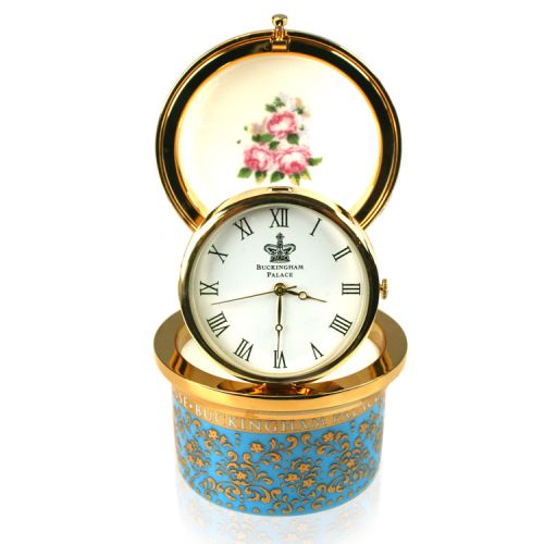 Royal coat of arms fine bone china pillbox clock featuring a lion and unicorn royal crest surrounded by ornated gold patterns and English flower patterns on a turquoise blue coloured background. Integrated pop-up clock on a gold plated hinge and decorated