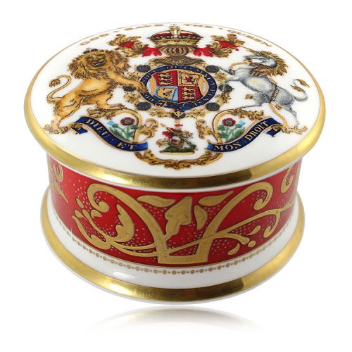 The official commemorative Coronation English fine bone china pillbox with a design featuring a royal coat of arms cicled by gold ornamental features on a red background border. 