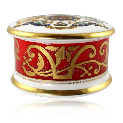 The official commemorative Coronation English fine bone china pillbox with a design featuring a royal coat of arms cicled by gold ornamental features on a red background border. 