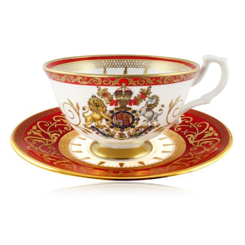 The official commemorative Coronation English fine bone china teacup and saucer with a design featuring a royal coat of arms circled by gold ornamental features on a red background border. 