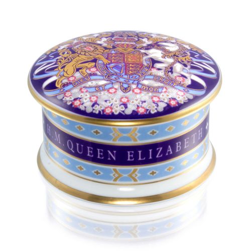 This pillbox has a lid with the lion and unicorn crest. The edge of the pillbox is gold, light blue and purple design. HM Queen Elizabeth reads on the edge of the pillbox
