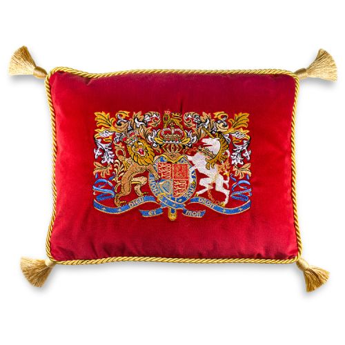 A  rectangular red velvet cushion with the lion and unicorn crest embroidered in the centre of the cushion. At each corner of the cushion is a gold tassel and a gold trim is round the edge of the cushion