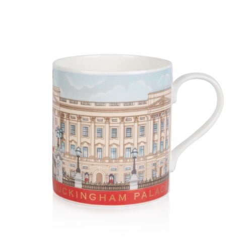 White mug with illustration of Buckingham Palace wrapping around the entire mug. Red strip at bottom with gold lettering that says 'Buckingham Palace'. Next to a matching biscuit tin and tea caddy and a gold tray of biscuits.