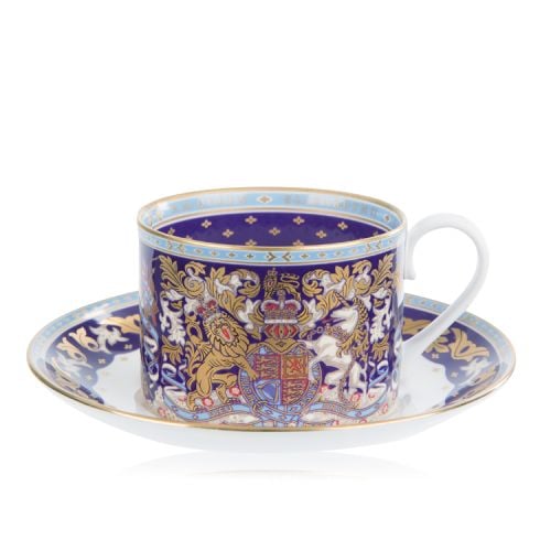The longest reigning monarch teacup and saucer. The saucer is stood behind the cup. With a white centre and a purple, gold and light blue edge. The cup is purple, light blue and gold with the lion and unicorn crest at the centre.