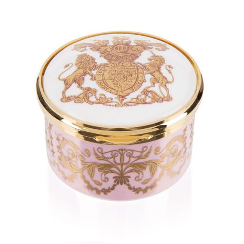 Pink, white and gold pillbox. The edge of the pillbox is pink with swirly gold design. The lid is white with the gold lion and unicorn crest