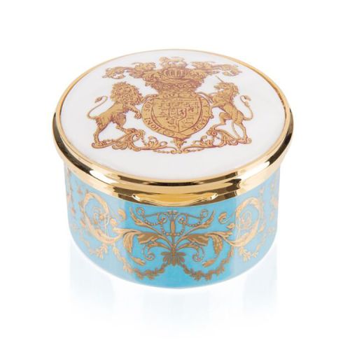 Turquoise, white and gold pillbox. The edge of the pillbox is turquoise with swirly gold design. The lid is white with the gold lion and unicorn crest