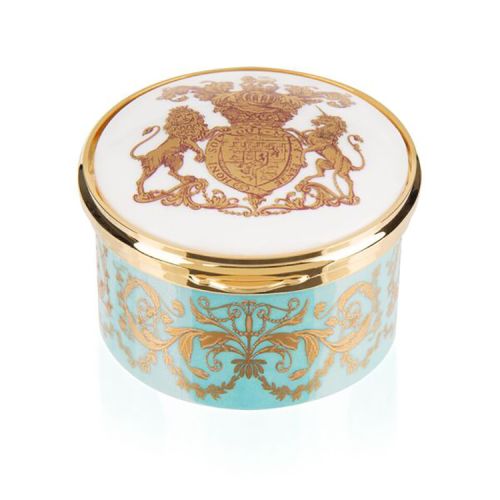 Green, white and gold pillbox. The edge of the pillbox is green with swirly gold design. The lid is white with the gold lion and unicorn crest