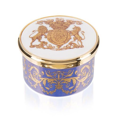 Purple, white and gold pillbox. The edge of the pillbox is purple with swirly gold design. The lid is white with the gold lion and unicorn crest