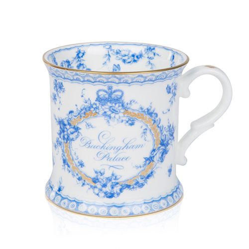 White tankard with a blue floral garland and bird design and finished with gold detail and gold edge of the tankard. At the centre of the tankard are the words 'Buckingham Palace' in blue