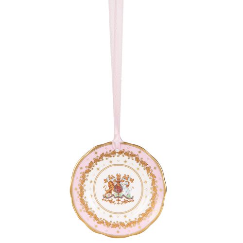 Miniature pink plate with gold crown detail. It is  hanging from a pink ribbon