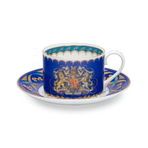 Teacup and saucer. Blue with white handle and gold accents. Royal coat of arms at the centre of the teacup.