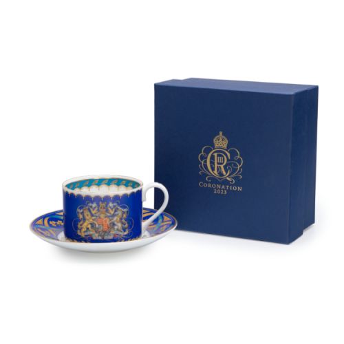 Teacup and saucer. Blue with white handle and gold accents. Royal coat of arms at the centre of the teacup.