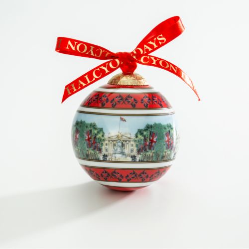 Christmas bauble depicting Buckingham Palace and the Victoria Memorial from The Mall. Including Union Flags and trees down The Mall. Finished with a red bow.
