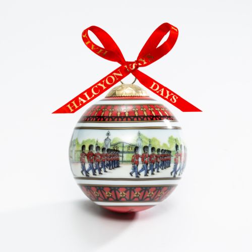 Christmas bauble depicting marching guards in the front court of Buckingham Palace. Finished with a red bow.