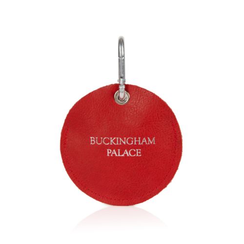 red circular pouch containing dog walking bags. The words 'Buckingham Palace' printed in silver on the front