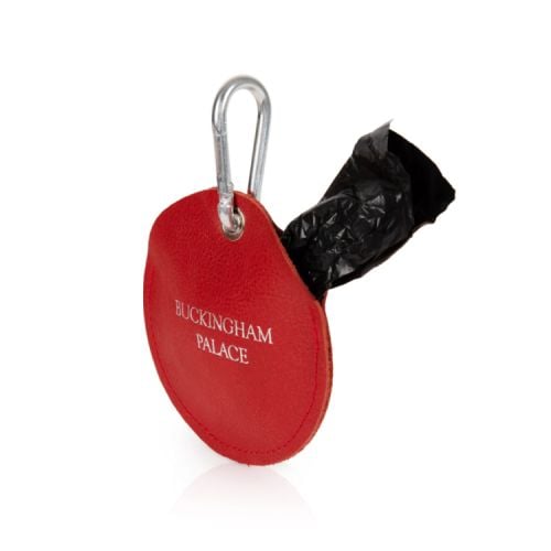 red circular pouch containing dog walking bags. The words 'Buckingham Palace' printed in silver on the front