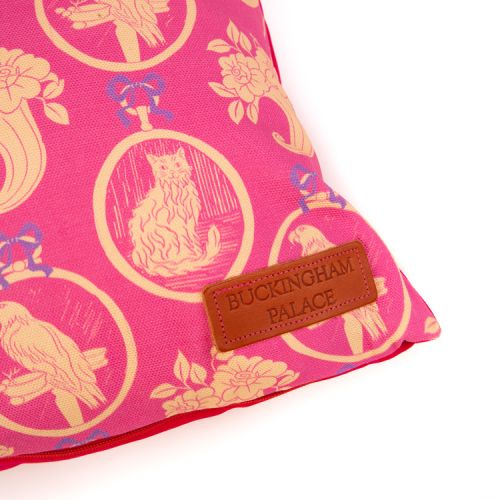 Rectangular cushion made with a pink material printed with yellow parrots and cats