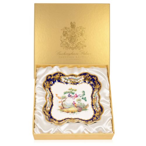 Square dish with a gold and blue ornate border. At the centre of the plate is a painted design of three exotic birds in a tree.