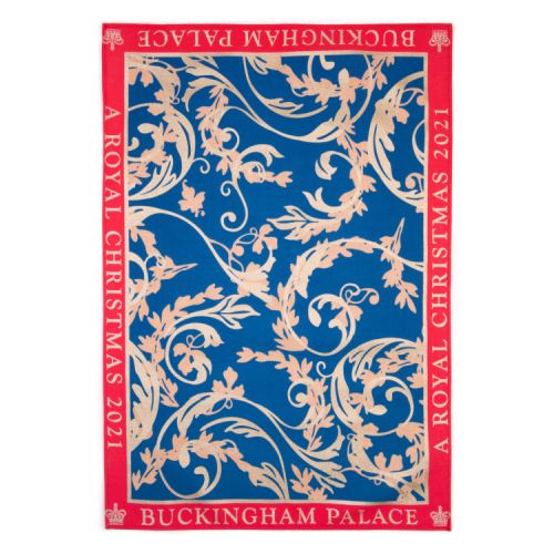A tea towel with a blue centre featuring a gold design. A red border reads the words 'Buckingham Palace A Royal Christmas 2021'