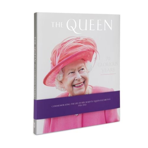 Front cover of The Queen 70 Glorious Years featuring a picture of The Queen in a pink outfit and hat. Purple band wrapped round the book to commemorate the life of Her Majesty.