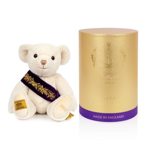 Merrythought teddy bear with a purple sash embroidered with gold leaf pattern and a gold tassel.
