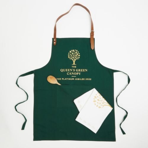 Green apron with brown leather straps. On the apron is a printed gold tree and the words 'The  Queen's Green Canopy The Platinum Jubilee 2022'