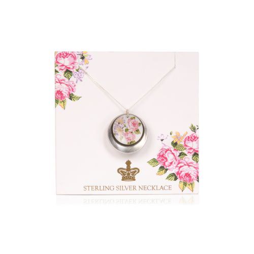 Circular rose pendant with a silver disc behind on a silver chain. It is on a pale pink backing card decorated with pink roses and a gold crown