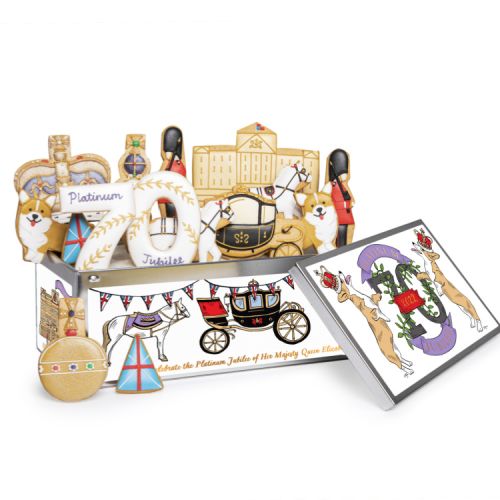 A selection of iced biscuits including carriages, the façade of Buckingham Palace, guardsmen and corgis. They are in an illustrated tin, decorated with corgis, carriages and 70. 