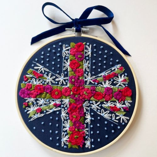 Round embroidery hoop with a navy back and embroidered with red and pink florals to create a union jack