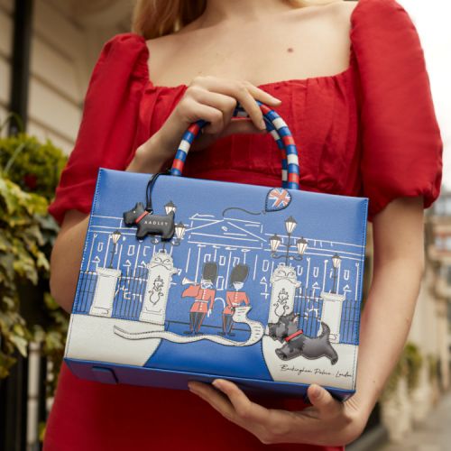 Blue handbag featuring an illustration of the front of Buckingham Palace, two guardsmen, and the black Scottie dog. The handles are red, white and blue.