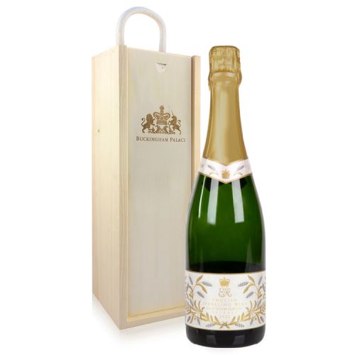 English Sparkling Wine green glass bottle with a label featuring EIIR and a gold leaf design in front of a wooden box etched with a lion and unicorn and the words 'Buckingham Palace'
