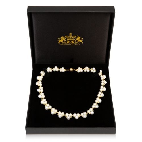 Single strand necklace with trios of pearls and gold beads covering the length.