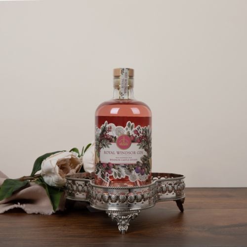 Front of pink gin bottle. Clear glass bottle with cork stopper. Label is illustrated with botanicals and flowers that are included in the drink.