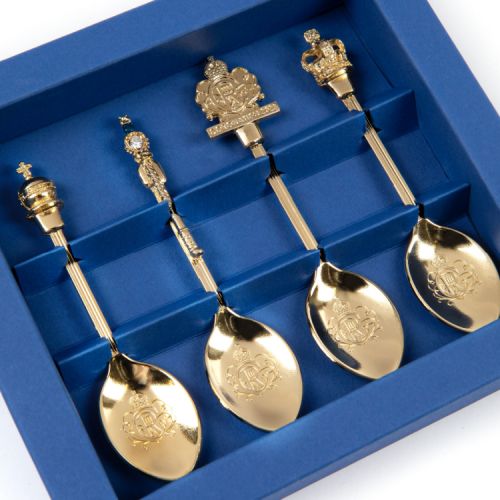 4 gold spoons with commemorative toppers. Presented in a blue box with perspex window