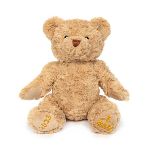 beige fluffy stuffed bear with '2023' on one foot and a crown on the other foot. 