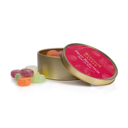 Top of tin of fruit selection. Red background on gold round tin with white illustrations featuring a variety of illustrations including teacup, fork and crown. 