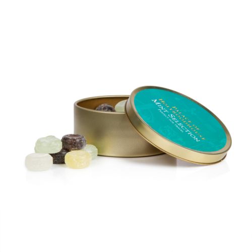 Top of tin of mint selection. Turquoise background on gold round tin with white illustrations featuring a variety of illustrations including teacup, fork and crown. 