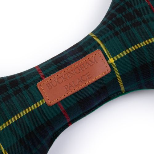 stuffed bone toy in a tartan fabric with a small rectangle leather label that reads BUCKINGHAM PALACE.