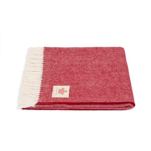 red herringbone blanket with white tassels, folded with the label facing upwards