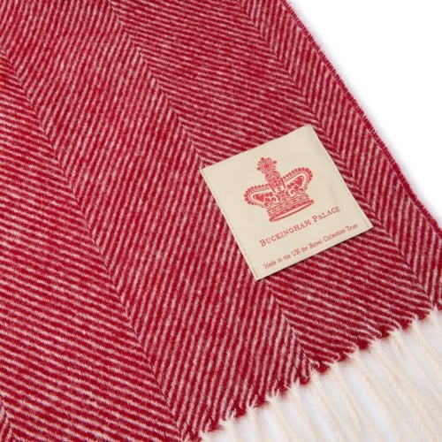red herringbone blanket with white tassels, folded with the label facing upwards