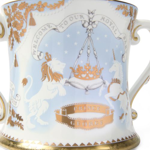 2013 limted edition number one Loving Cup featuring a lion and unicorn with gold detailing adjacent to a blue box with "Welcome to our Royal Baby" embossed in gold. 