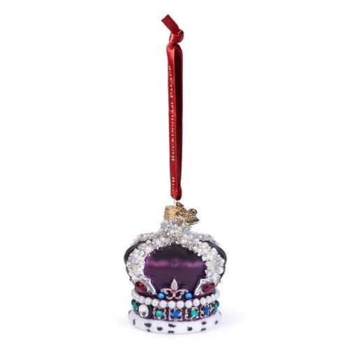 Glass Christmas ornament shaped like an ornate royal crown, finished in deep purple with silver detailing and decorated with faux pearls and multicoloured jewel accents. The crown features a white ermine-style trim with black spots and hangs from a red ri