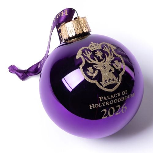 Palace of Holyroodhouse 2026 glass bauble in deep purple with gold crest and text, suspended from a ribbon printed ‘Palace of Holyroodhouse’.
