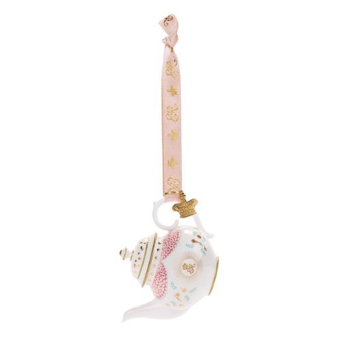 Decorative hanging teapot ornament featuring a white teapot with pink floral panels, gold accents, and delicate blue floral detailing. The ornament hangs from a pale pink ribbon decorated with gold crown motifs and includes a gold crown charm attached abo