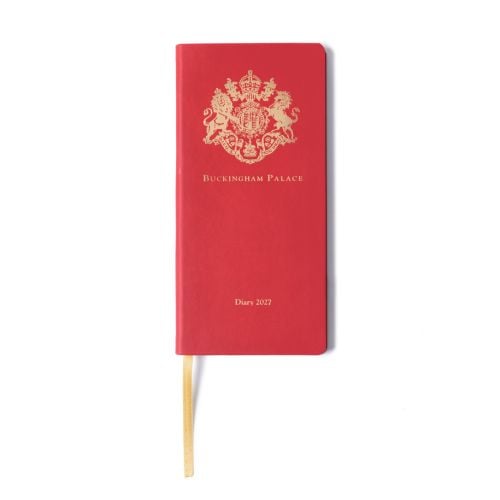 Closed Buckingham Palace 2027 diary with a red cover and rounded corners. A gold Buckingham Palace crest is embossed at the top, with “Buckingham Palace” printed beneath and “Diary 2027” centred near the bottom. A gold ribbon bookmark extends from the bas