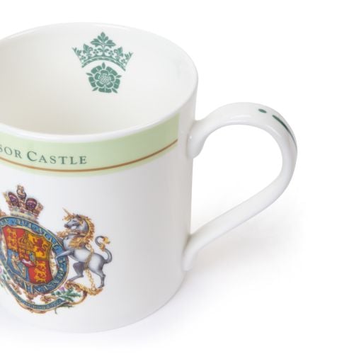White ceramic mug with a green band and gold trim reading “Windsor Castle,” featuring a detailed Royal Coat of Arms with a lion and unicorn.

